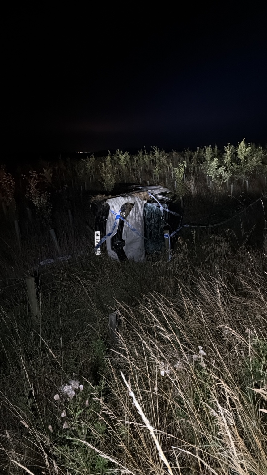Car on its side at a night-time recovery scene