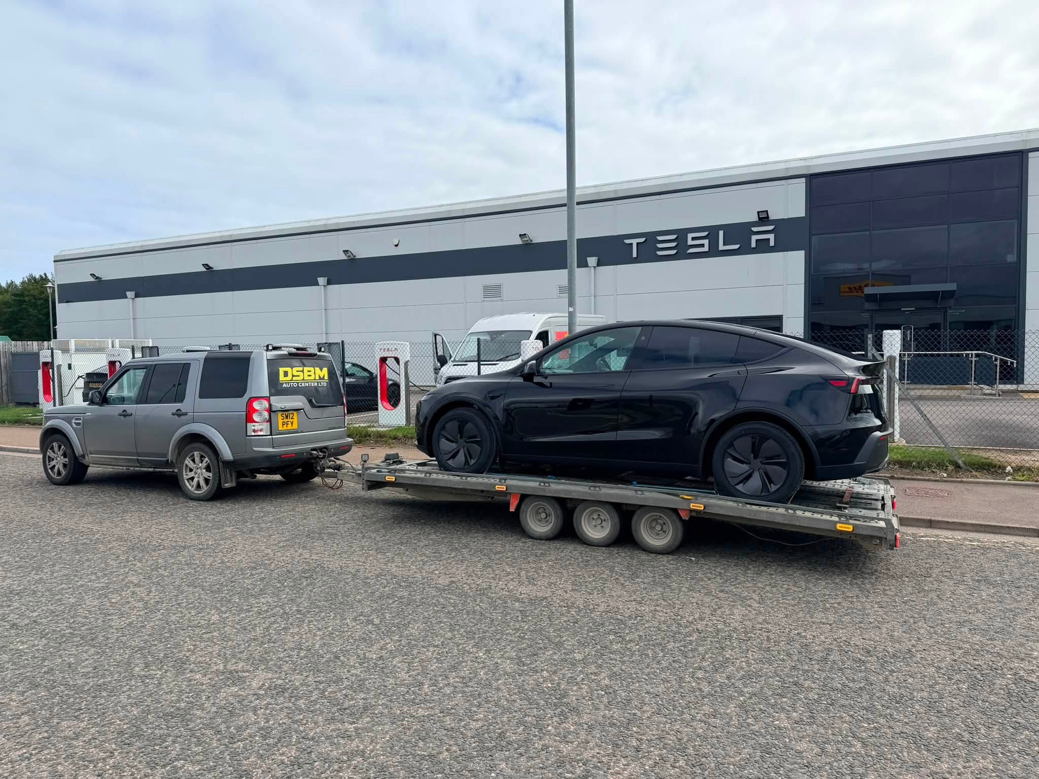 Tesla secured on the DSBM transporter beside the Discovery at a vehicle collection